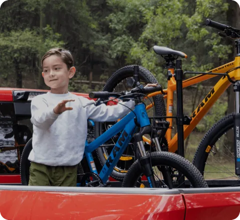 Niño junto a bicicletas RAM en la caja de una camioneta